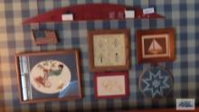 lot of decorative wall hangings including needlepoint and sailboat wall hanging